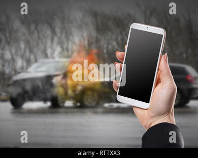 Avec le téléphone main de femme sur fond d'un accident de voiture Banque D'Images