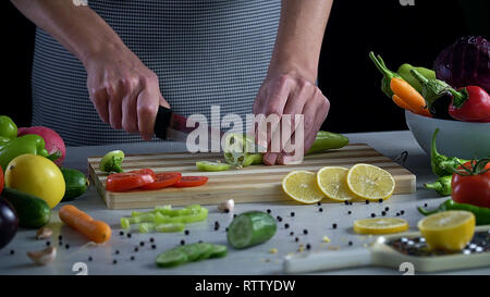 L'homme est couper des légumes dans la cuisine, le tranchage poivron vert Banque D'Images