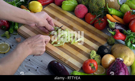 L'homme est couper des légumes dans la cuisine, le tranchage poivron vert Banque D'Images