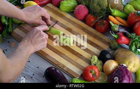 L'homme est couper des légumes dans la cuisine, le tranchage poivron vert Banque D'Images