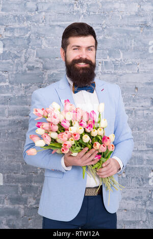 Homme romantique avec des fleurs. Cadeau romantique. Macho prêt date romantique. En attente de Darling. Tulipes pour ma chérie. Homme très soigné porter Bow-tie tuxedo tenir fleurs bouquet. Inviter ses sorties. Banque D'Images