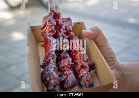 Un homme délicieux barbecue achats mariné brochettes dans une boîte en carton à emporter à un récipient biodégradable marché alimentaire à Christchurch, Nouvelle-Zélande Banque D'Images