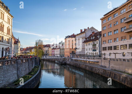 Vue depuis le pont Tromostovje vers les maisons, les gens qui marchent le long de la rivière Ljubljanica à au sud du centre-ville, Ljubljana, Slovénie Banque D'Images