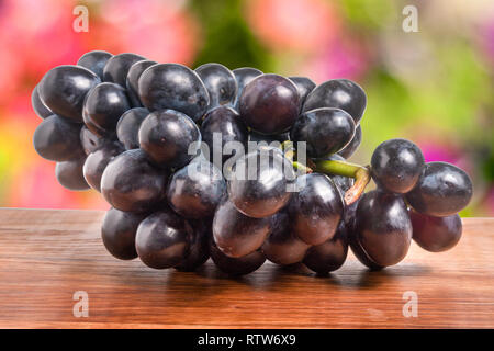 Bouquet de raisin bleu sur une table en bois avec arrière-plan flou Banque D'Images