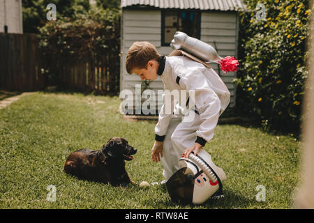 Petit garçon dans un costume d'astronaute jouer dehors avec son chien. Kid faisant semblant d'être un astronaute passer du temps avec son chien. Banque D'Images