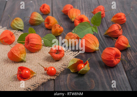 Physalis éparpillés sur une table en bois foncé Banque D'Images