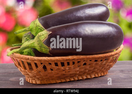 L'aubergine dans un panier en osier sur la table en bois avec arrière-plan flou Banque D'Images