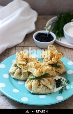 Crêpes farcies de sacs de hareng, servi avec caviar, crème aigre et aneth sur un fond de bois. De style rustique, selective focus. Banque D'Images