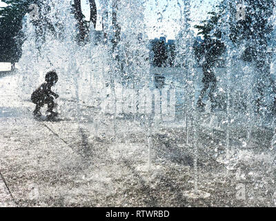 Les projections de l'enfant est l'eau douce dans la région de Fontaine à sec sur jour ensoleillé chaud Banque D'Images