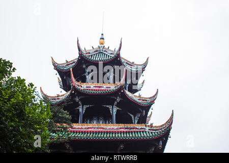 Toit pagode bâtiment avec détails et arbre en face. Toit à plusieurs niveaux, les bardeaux colorés et élaborer des ornements et décorations. Banque D'Images