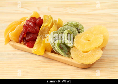 Les morceaux de kiwi, papaye, mangue, ananas et fraises, allongé sur une plaque de bambou sur une table en bois. Macro. Libre Banque D'Images