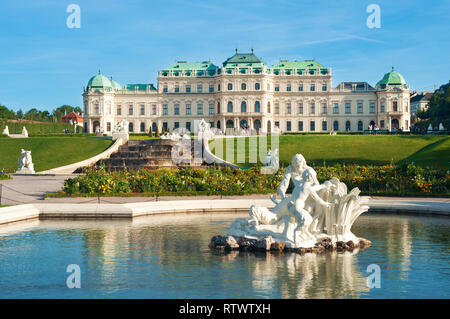 Vue sur le palais du Belvédère, fontaine, parterre de fleurs et plusieurs statues blanches de personnes dans l'eau d'un étang contre un ciel bleu Banque D'Images