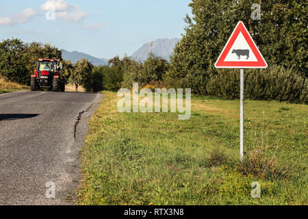 Liptovsky Hradok, Slovaquie - Août 22nd, 2018 : Attention les vaches panneau de passage à niveau, à côté du tracteur routier avec entrée, campagne, collines et montagnes en dist Banque D'Images