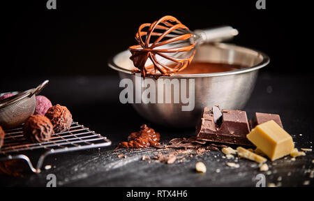 Fouetter enrobées de chocolat posée sur un récipient rempli de chocolat fondu ou de la sauce avec une grille de bonbons et ingrédients Banque D'Images