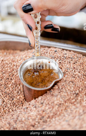Le café arabe, turque traditionnelle brassée dans de petites tasses de cuivre en sable chaud. Close up shot Banque D'Images