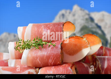 Tranches de bacon typique du Tyrol du Sud se trouvant en face de montagnes des Alpes Banque D'Images