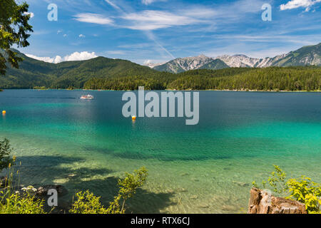 Vue sur le lac d'Eibsee Garmisch-Partenkirchen, Allemagne en été à une chaîne de montagnes lointaines avec un ferry touristique sur l'eau. Banque D'Images