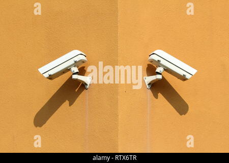 Deux caméras de surveillance blanc avec boîtier métallique robuste monté sur la construction de complexes industriels coin sur chaude journée ensoleillée Banque D'Images