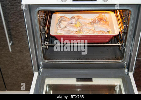 Délicieux avec du poulet rôti et des pommes de terre, crues ingrédients dans une casserole en céramique dans un four chaud pour un dîner en famille Banque D'Images