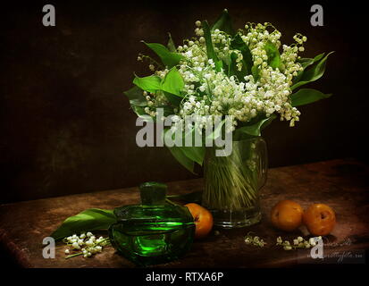 Nature morte aux abricots et un bouquet de lys de la vallée sur un fond brun Banque D'Images