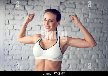 Fit young woman showing bicepses portrait Banque D'Images