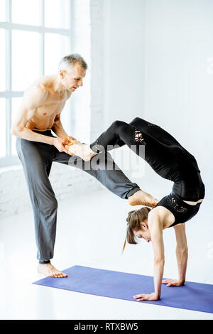 Young woman practicing yoga avec formateur expérimenté dans le livre blanc de spacieux studios Banque D'Images
