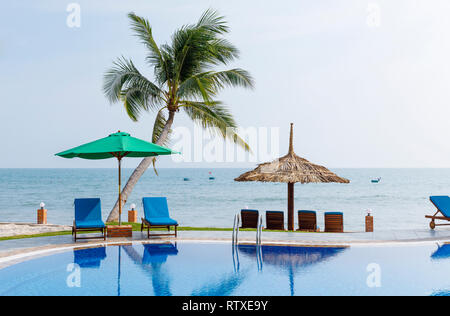 NAM TIEN, VIETNAM - 15 février 2018 : Des chaises longues et des nuances sous les palmiers autour d'une piscine extérieure aménagée dans Nam Tien, Vietnam le 15 février, 2018 Banque D'Images