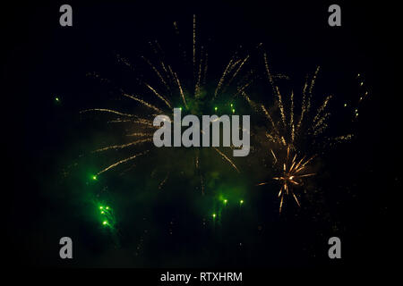 Plusieurs couleurs orange et vert d'artifice explosion de couleurs dans le ciel. De beaux effets pyrotechniques avec mousseux Banque D'Images