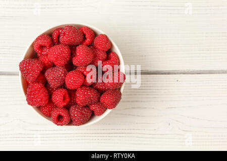 Vue sur table, petite tasse de porcelaine rempli de framboises sur les tableaux blancs 24. Banque D'Images