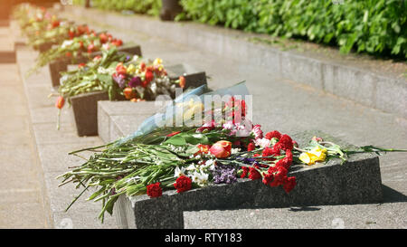 Des fleurs au monument de granit. Fleurs placées à un monument pour le jour de la victoire de la Seconde Guerre mondiale. La mémoire des défenseurs de la patrie. Banque D'Images