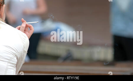 Femme main tenant la cigarette. Femme cigarette à l'extérieur, vue de dos. Habitude nuisible concept. Banque D'Images