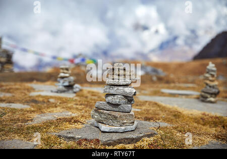 Tas de pierres et de drapeaux de prière Tibetains Lung Ta au camp de base à l'Himal Mardi Nuageux sommets de montagnes de l'Himalaya au Népal Banque D'Images