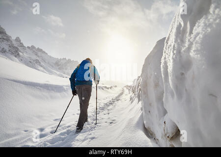 Sac à dos bleu touristique avec la marche sur la route de la neige dans les montagnes de neige au Banque D'Images