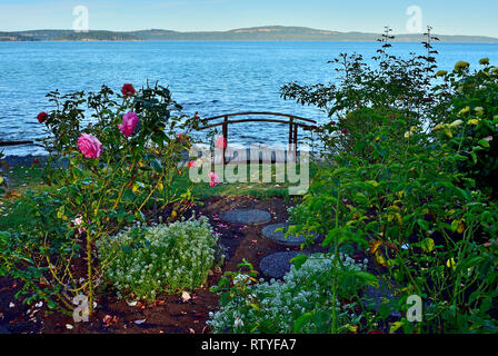 Un jardin de roses surplombant le bord de l'eau et une petite passerelle pour piétons à l'auberge de la mer centre de vacances près de Nanaimo sur l'île de Vancouver Banque D'Images