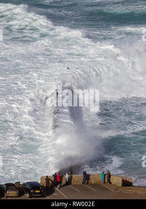 Sennen, Cornwall, UK. Le 3 mars 2019. Des coups de vent et des vagues hautes de 20 pieds lash le granite abruptes de Cornwall. Les cavaliers de l'audace de se faire prendre par des énormes vagues submergeant l'embarcadère. Crédit : Mike Newman/Alamy Live News. Banque D'Images