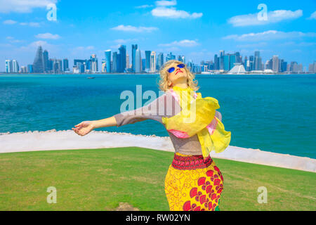 Le Qatar travel concept. Carefree woman enjoyis les vues de Doha West Bay. Tourisme à Doha blonde de l'Est du centre-ville vue Mound-Skyline Banque D'Images