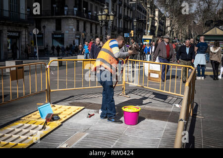 Un opérateur vu travailler au lieu de mémoire dans le centre de Las Ramblas parmi une foule de piétons. Les travaux d'installation sont en cours à l'emplacement mémorial des victimes de l'attaque terroriste dans le quartier de Las Ramblas de Barcelone le 17 août 2017 lorsqu'un van volontairement envahi le centre de la marche qui a fait de nombreux blessés. Banque D'Images