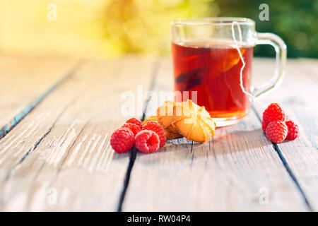 Plateau bouillis dans un sac des framboises et des biscuits sur une table en bois, sur une journée ensoleillée Banque D'Images