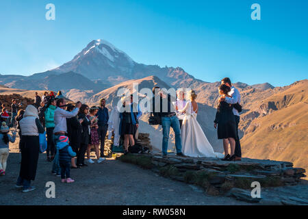 Stepantsminda, Géorgie - 06.10.2018 : photographe pousses jeunes mariés sur l'arrière-plan du Mont Kazbek, Géorgie Banque D'Images