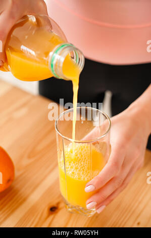 Femme dans un survêtement de verser le jus d'orange à la maison Banque D'Images