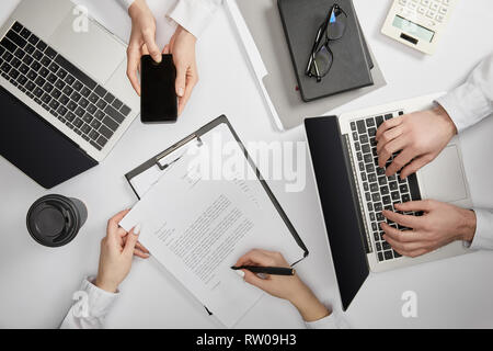Vue de dessus d'entrepreneurs de la saisie sur ordinateur portable, smartphone et document signature holding Banque D'Images