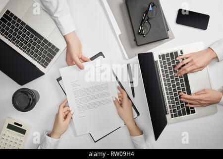 Vue de dessus d'entrepreneurs de la saisie sur ordinateur portable et holding document Banque D'Images