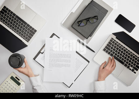 Portrait of office worker holding paper cup et typing on laptop Banque D'Images