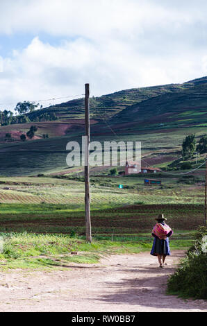 Vieille Femme autochtone avec des vêtements traditionnels de la ville de Cusco, marchant sur un chemin. Banque D'Images