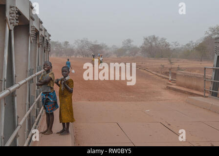 Photo de deux fiers et souriant des enfants ghanéens locales portant des vêtements traditionnels et posant pour la photo sur un pont local. Banque D'Images