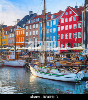 Les touristes à pied du remblai de Nyhavn avec des bateaux amarrés au coucher du soleil, Copenhague, Danemark Banque D'Images