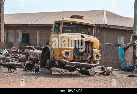 Une épave d'un vieux camion jaune à gauche une rue à Bolgatanga, Ghana, Afrique de l'Ouest Banque D'Images