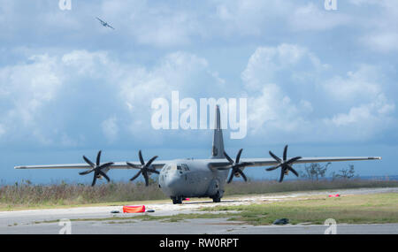 Un U.S. Air Force C-130J Super Hercules est situé sur la ligne de vol de Tinian, U.S. Commonwealth des îles Mariannes du Nord comme un C-130H Hercules du Japon d'autodéfense va à la distance, le 27 février 2019 lors de l'exercice Faire face au Nord 19. Par le biais d'exercices et d'engagements au cours de faire face au nord, la United States Air Force, Japan Air Self-Defense Force et de la Royal Australian Air Force augmenter l'interopérabilité pour l'aide humanitaire et des opérations de secours. (U.S. Air Force photo par le Sgt. III) JT Mai Banque D'Images