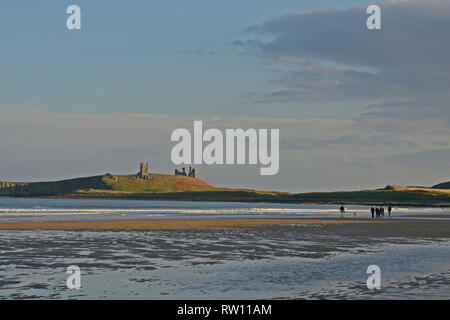 Château de Dunstanburgh dans Northumberland avec peu de personnes sur la plage et dans une lumière attrayante Banque D'Images