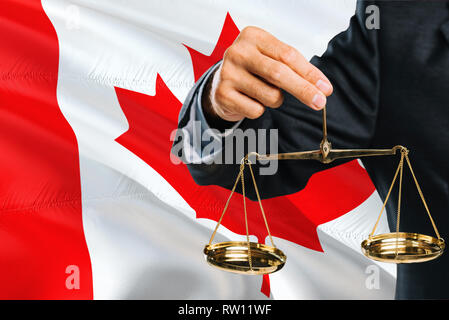 Le Juge canadien est maintenant golden balance de la justice avec le Canada waving flag background. Thème de l'égalité juridique et concept. Banque D'Images